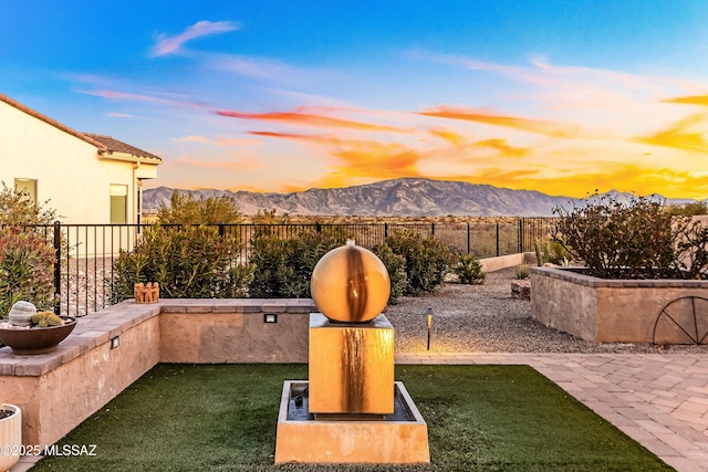 patio terrace at dusk with a mountain view and a yard