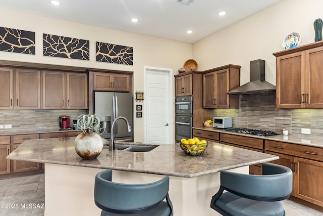 kitchen with appliances with stainless steel finishes, sink, a kitchen bar, and wall chimney exhaust hood