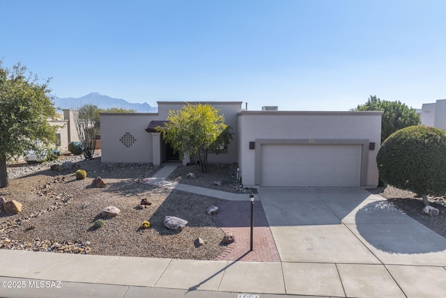 pueblo-style home featuring a garage and a mountain view