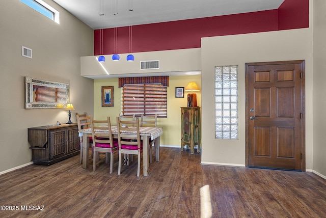 dining area featuring a healthy amount of sunlight, dark hardwood / wood-style floors, and a high ceiling