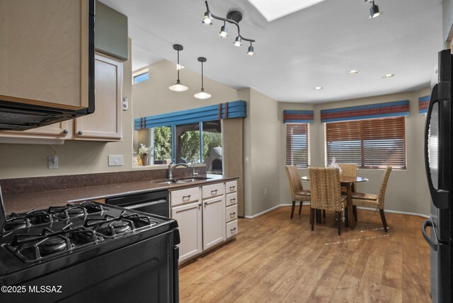 kitchen with sink, white cabinets, hanging light fixtures, black appliances, and light wood-type flooring