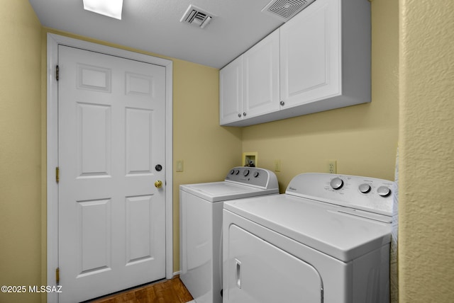 clothes washing area featuring cabinets, dark wood-type flooring, and washer and dryer