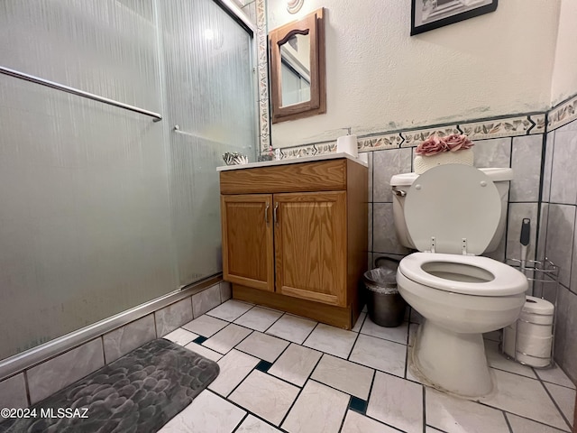 bathroom featuring vanity, tile walls, toilet, and walk in shower