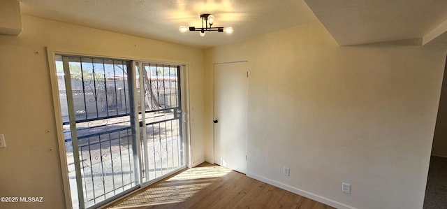 doorway with a wall unit AC, a chandelier, and light hardwood / wood-style flooring