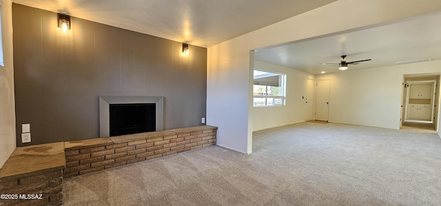 unfurnished living room with a brick fireplace, light carpet, and ceiling fan