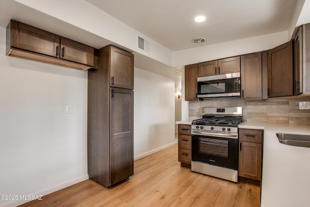 kitchen with tasteful backsplash, sink, light hardwood / wood-style floors, and appliances with stainless steel finishes