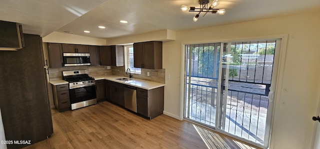 kitchen featuring sink, light wood-type flooring, appliances with stainless steel finishes, a healthy amount of sunlight, and backsplash