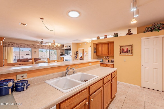 kitchen with sink, decorative light fixtures, ceiling fan with notable chandelier, and light tile patterned flooring