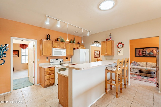 kitchen featuring light tile patterned flooring, a kitchen breakfast bar, kitchen peninsula, light brown cabinets, and white appliances