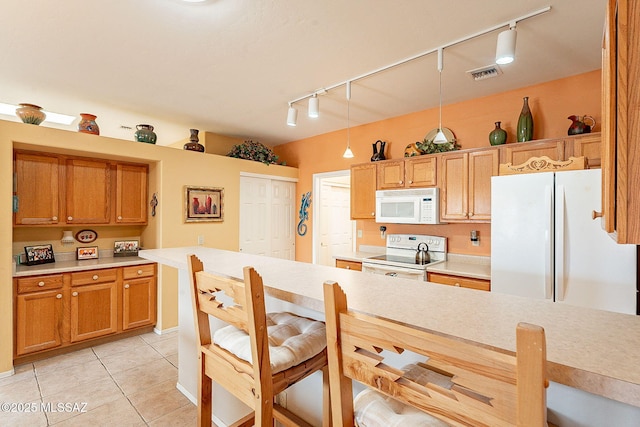 kitchen featuring pendant lighting, white appliances, track lighting, and light tile patterned floors