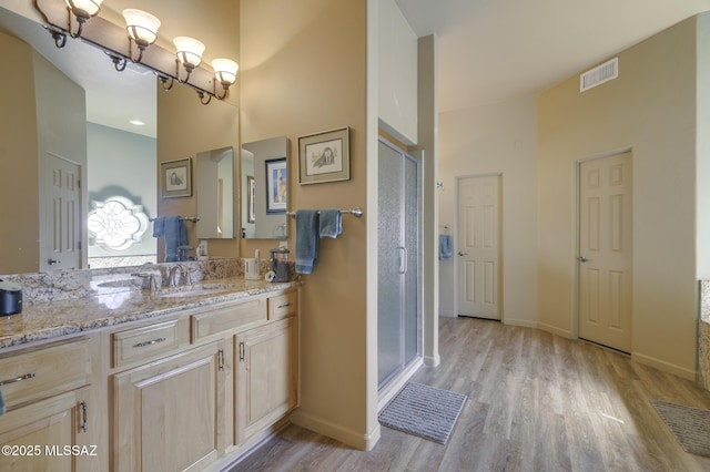 full bathroom featuring visible vents, a shower stall, baseboards, wood finished floors, and vanity