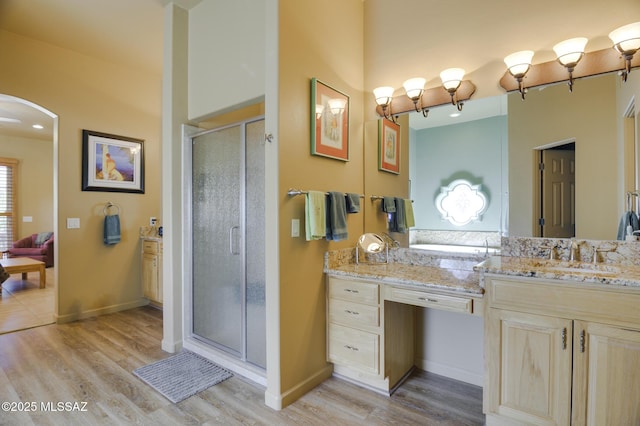 bathroom featuring vanity, a shower stall, wood finished floors, and baseboards