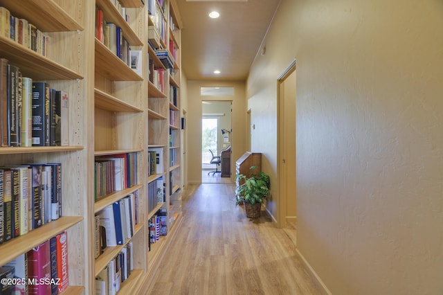hallway featuring light wood finished floors, recessed lighting, and baseboards