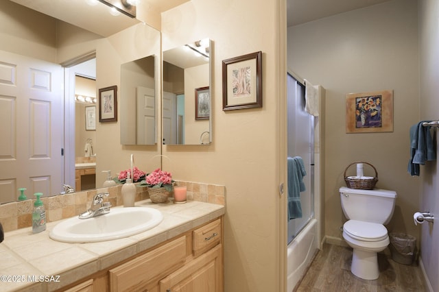 bathroom with enclosed tub / shower combo, toilet, vanity, and wood finished floors
