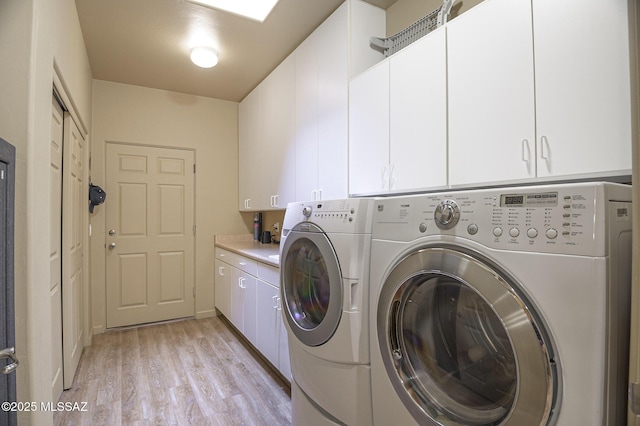 laundry area with cabinet space, separate washer and dryer, and light wood finished floors