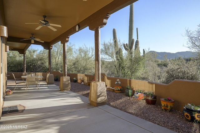 view of patio with outdoor dining area, ceiling fan, a mountain view, and fence