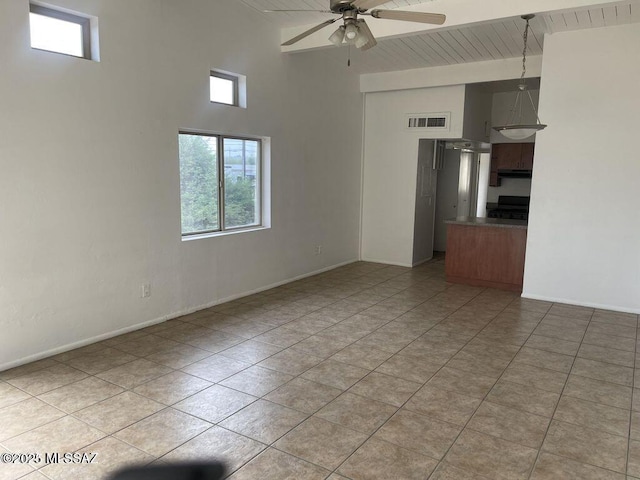 tiled empty room featuring a towering ceiling and ceiling fan