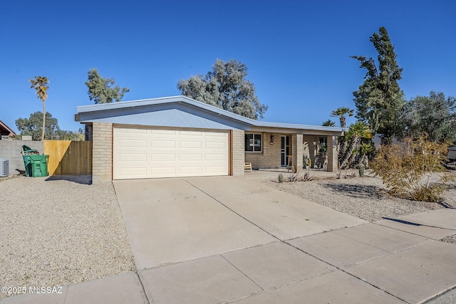 ranch-style home featuring a porch, an attached garage, fence, concrete driveway, and brick siding