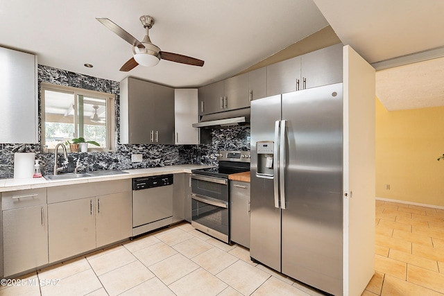 kitchen featuring gray cabinets, light tile patterned floors, under cabinet range hood, appliances with stainless steel finishes, and a sink