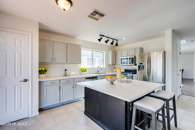 kitchen featuring a kitchen island, appliances with stainless steel finishes, tasteful backsplash, sink, and a kitchen breakfast bar