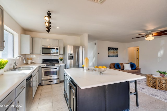 kitchen with sink, light tile patterned floors, appliances with stainless steel finishes, a kitchen island, and backsplash