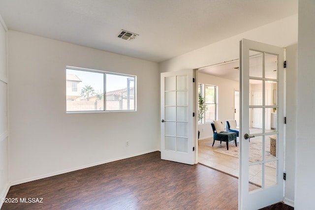 spare room with dark hardwood / wood-style floors and french doors