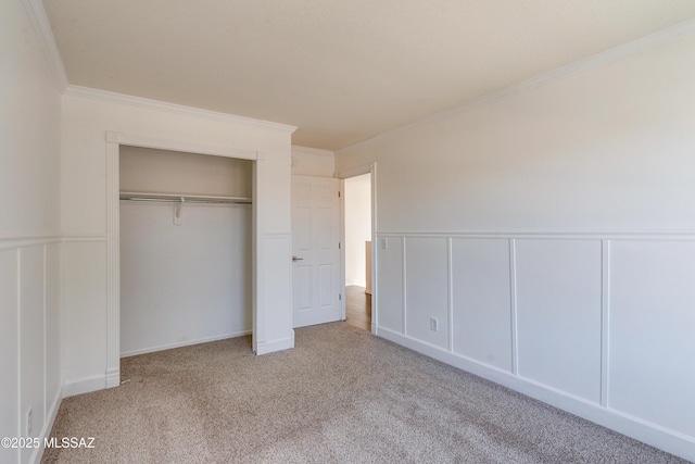 unfurnished bedroom with crown molding, light colored carpet, and a closet