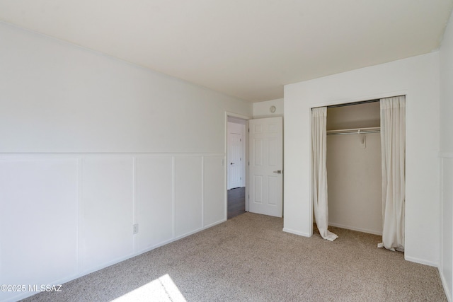 unfurnished bedroom with light colored carpet and a closet