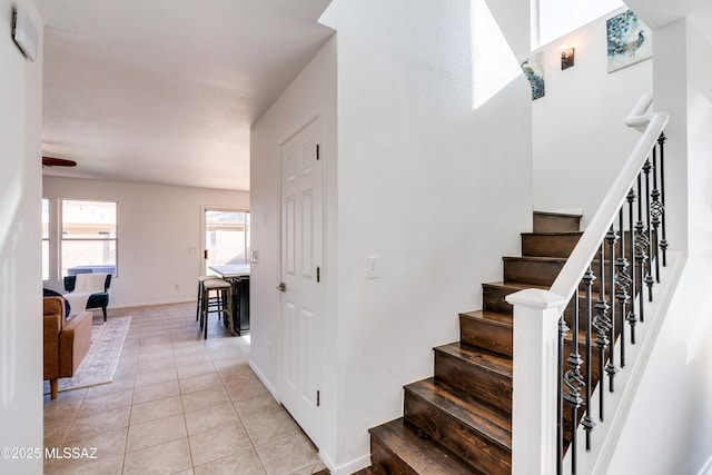 staircase featuring tile patterned flooring and ceiling fan