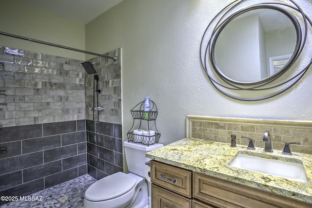 bathroom with vanity, toilet, and tiled shower