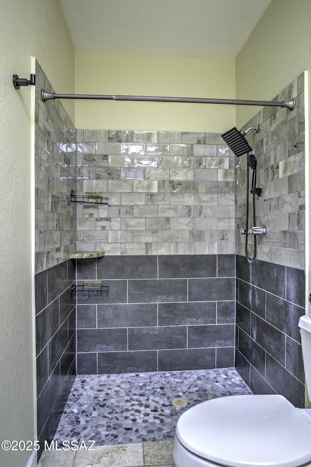 bathroom with tiled shower and toilet