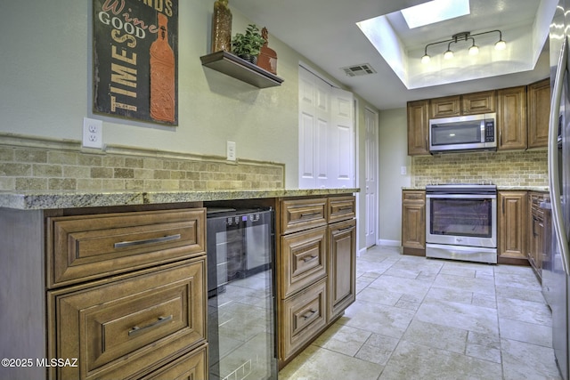 kitchen with wine cooler, tasteful backsplash, a skylight, a raised ceiling, and stainless steel appliances