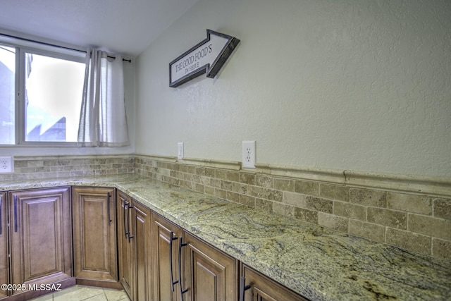 kitchen with light tile patterned floors, backsplash, and light stone counters