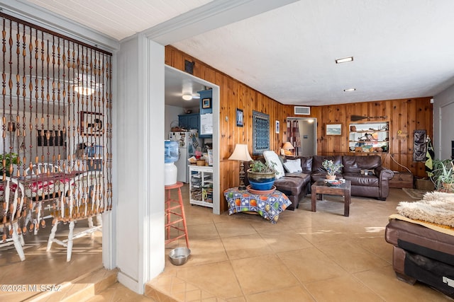 living room featuring tile patterned flooring and wooden walls