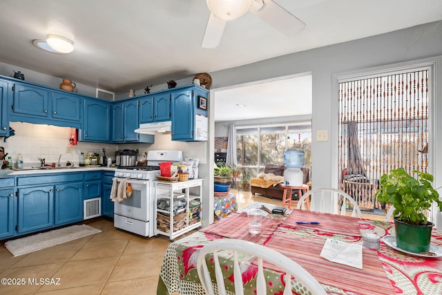 kitchen featuring blue cabinets, light tile patterned flooring, sink, and white gas stove