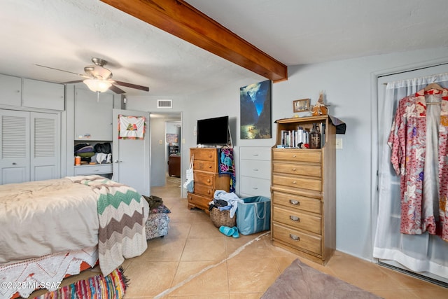 tiled bedroom featuring beamed ceiling, ceiling fan, and a closet