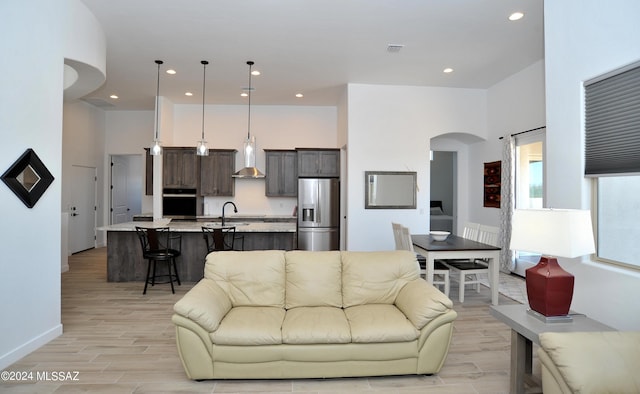 living room featuring sink, a towering ceiling, and light wood-type flooring