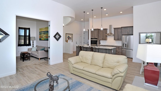 living room featuring sink, light hardwood / wood-style flooring, and a high ceiling