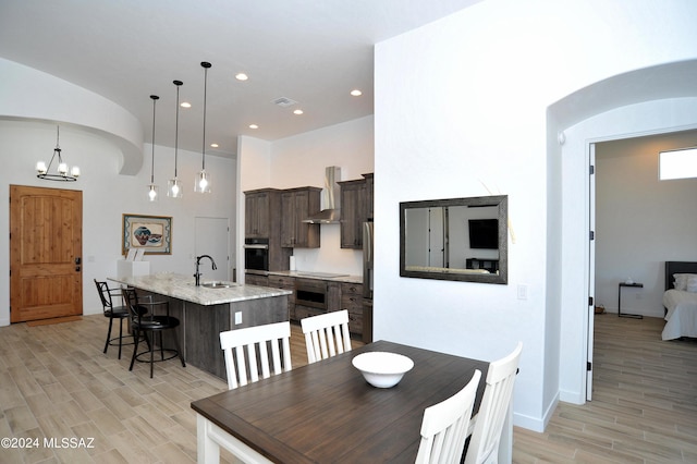 dining space with sink, a notable chandelier, and light wood-type flooring