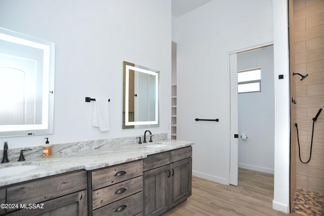 bathroom featuring vanity, wood-type flooring, and a tile shower