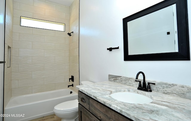 full bathroom with vanity, tiled shower / bath, and toilet