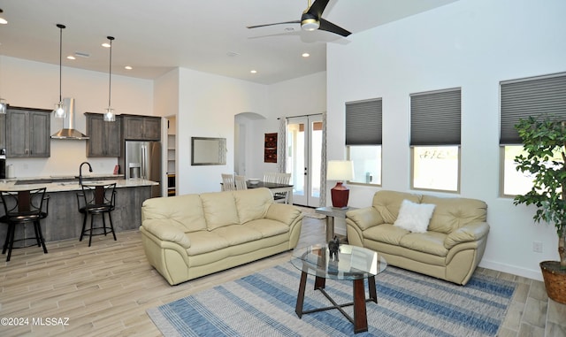 living room with sink, a towering ceiling, and light hardwood / wood-style flooring