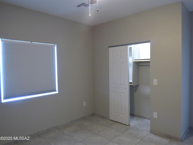 unfurnished bedroom featuring light tile patterned floors, a closet, visible vents, and baseboards