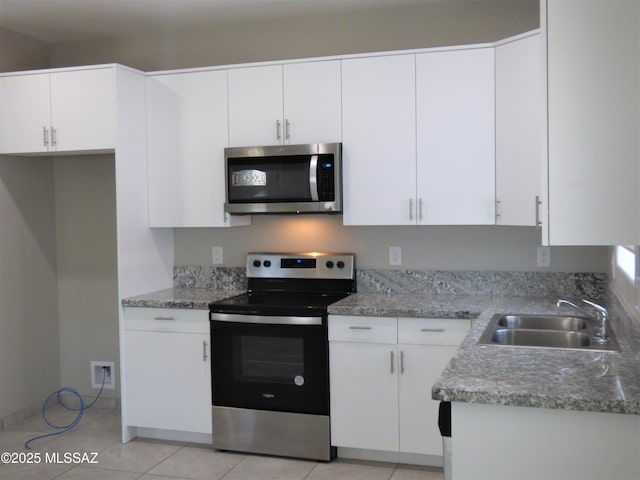 kitchen with white cabinets, light stone counters, stainless steel appliances, a sink, and light tile patterned flooring