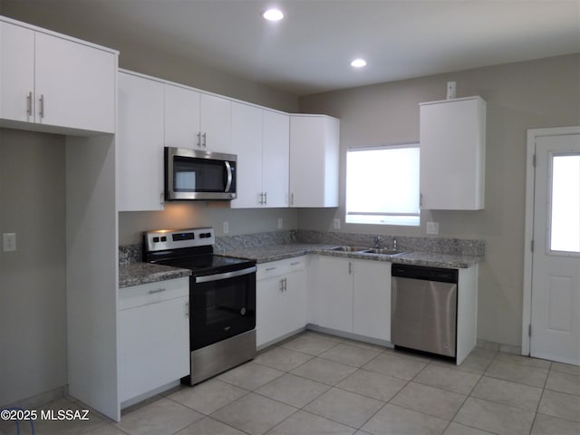 kitchen featuring stainless steel appliances, recessed lighting, stone countertops, white cabinets, and a sink