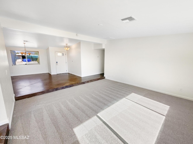 unfurnished living room with a chandelier and dark colored carpet