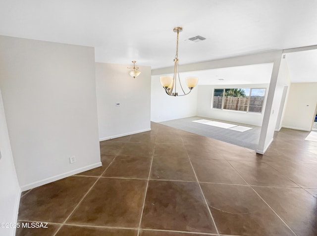 unfurnished dining area with dark tile patterned floors and an inviting chandelier