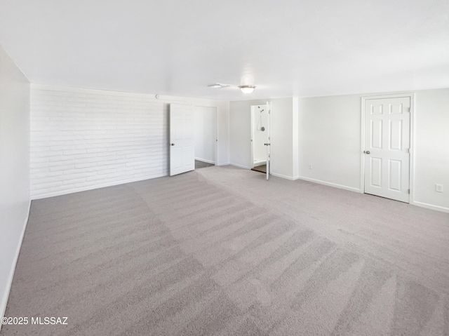 spare room featuring light colored carpet and brick wall