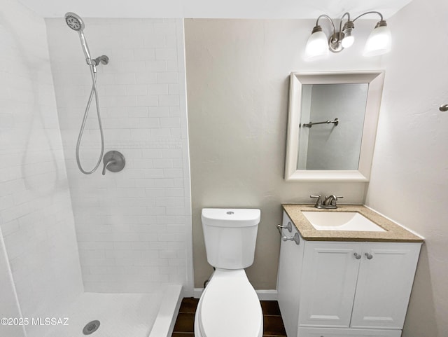 bathroom with vanity, toilet, and tiled shower