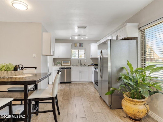 kitchen featuring white cabinetry, appliances with stainless steel finishes, sink, and light hardwood / wood-style flooring